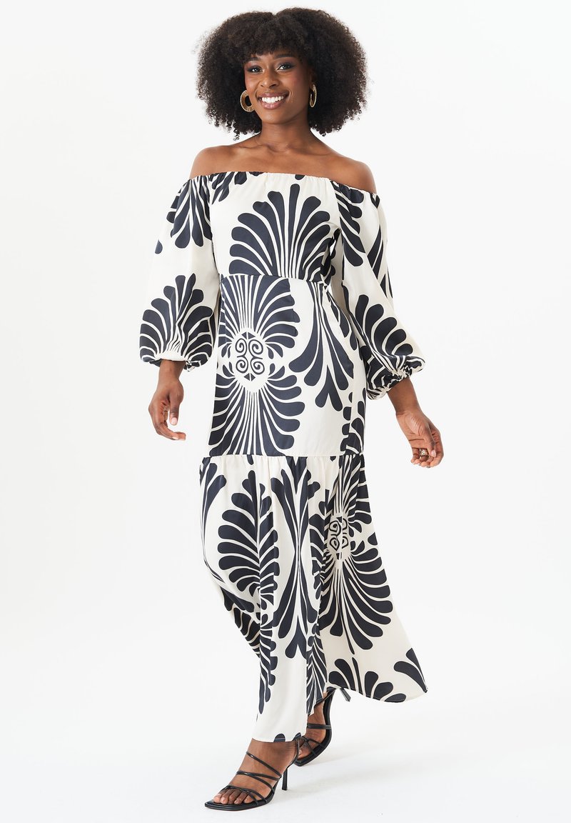 Off-the-shoulder maxi dress in black and white, featuring bold floral patterns, puffed sleeves, and a flowing silhouette.