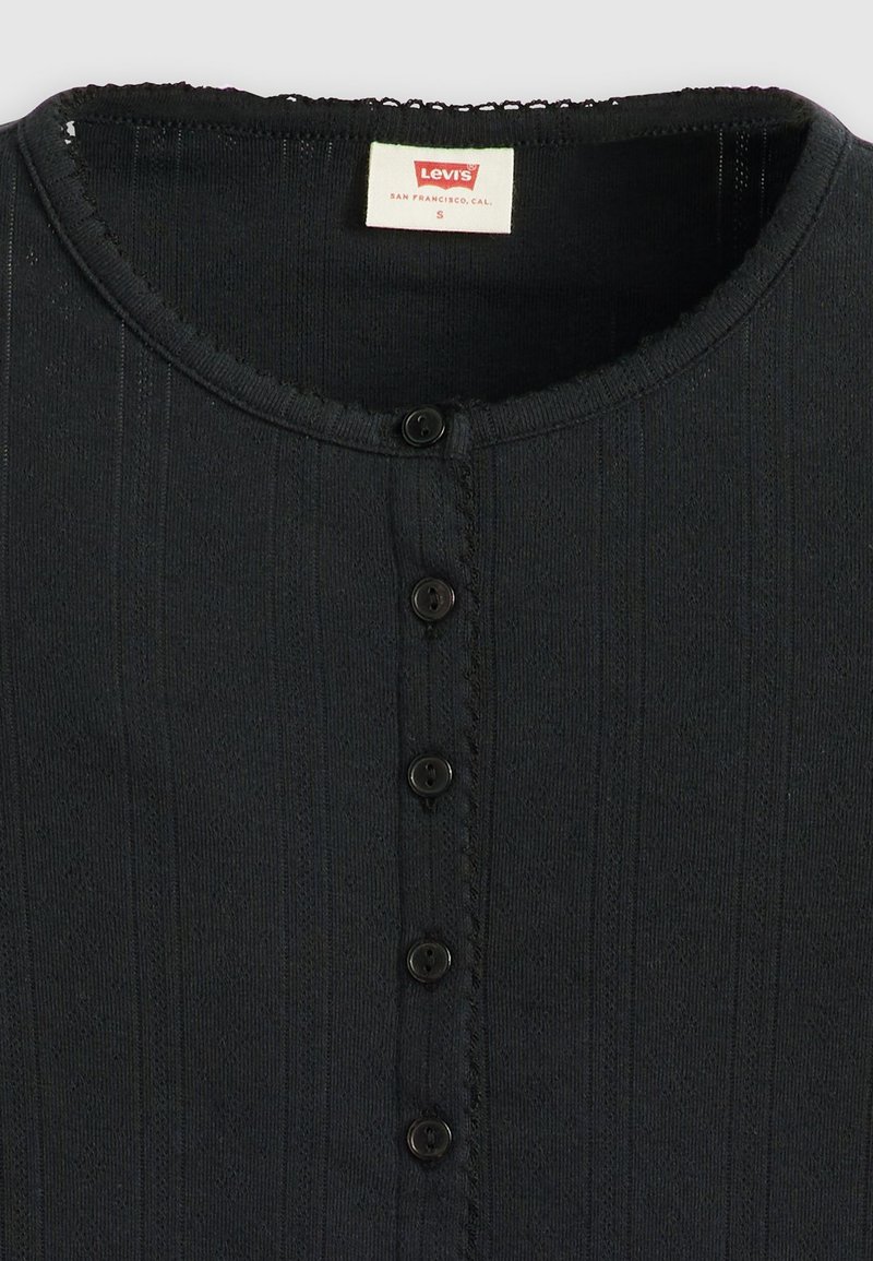 Haut en tricot noir à côtes avec col rond, cinq boutons noirs sur le devant et une étiquette blanche Levi's à l'intérieur du col.