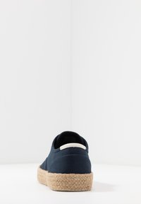 Zapato de lona azul marino con suela de cuerda de yute y detalle blanco en el talón; diseño de corte bajo con textura lisa y punta redonda.