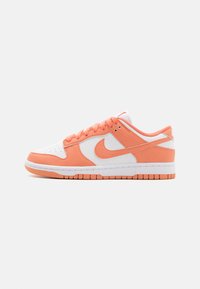 Nike Dunk-sneakers har en hvit lær tåboks og midtdel, med oransje nubuck-detaljer og en gummisåle i matchende oransje.