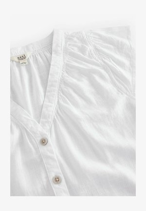 Weiße Button-Up-Bluse aus leichtem Stoff. Mit V-Ausschnitt, strukturierten Rüschen und kleinen Knöpfen entlang der vorderen Öffnung.