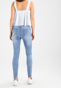 Ljust blått crop-top med rå kant, matchat med ljusblå skinny jeans. Jeansarna har bakfickor och bärs med vita sneakers.