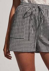 Zwart-witte geruite shorts met elastische tailleband, koordsluiting en zijzakken. De stof lijkt licht en textuurvol te zijn.