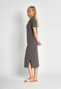 Graues knielanges Kleid mit kurzen Ärmeln, seitlichen Schlitzen, glatter Textur, getragen mit hellbeigen geflochtenen Riemchensandalen. Minimalistisches Design.