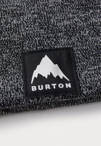 Căciulă tricotată în culori negru și gri, cu un model texturat. Prezintă o petrecere neagră cu un logo alb de munte și textul "BURTON".