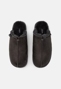 Een paar donkergrijze instapslippers met een zachte, fluffy binnenvoering en ronde, gesloten tenen, van bovenaf bekeken op een witte achtergrond.