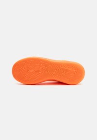 Sola de tênis de borracha laranja com um padrão texturizado e logótipo. Forma arredondada com ranhuras para tração e flexibilidade.
