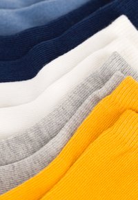 Set di calzini in tonalità di blu, bianco, grigio e giallo, caratterizzati da una texture rigata e un tessuto liscio. Ogni coppia è impilata in modo ordinato.