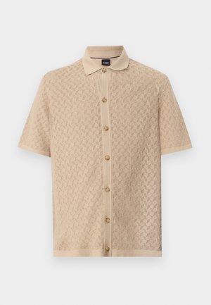 Chemise en maille beige à manches courtes, boutonnée sur le devant, motif géométrique texturé et col classique.