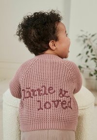 Cardigan rosa lavorato a maglia con un motivo testurizzato, che presenta le frasi "little" e "& loved" ricamate in bordeaux sulla parte posteriore.