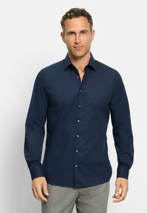 Navyblaue Langarmhemd mit Knopfleiste aus glattem Stoff, ausgestattet mit einem Kentkragen und hellen Knöpfen, getragen mit grauen Hosen.
