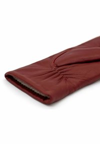 Red leather glove with soft, textured surface. Features gathered detail at the wrist, unlined interior, and smooth, sleek design.