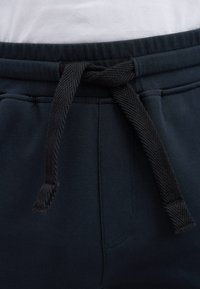 Dunkelblaue Sweatpants mit einem strukturierten schwarzen Kordelzug; ausgestattet mit einem elastischen Bund und seitlichen Einschubtaschen, aus einem weichen Baumwollgemisch gefertigt.