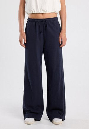 Navy wide-leg pants made from soft fabric, featuring an elastic waistband with a drawstring. Relaxed fit extends to the ankle.