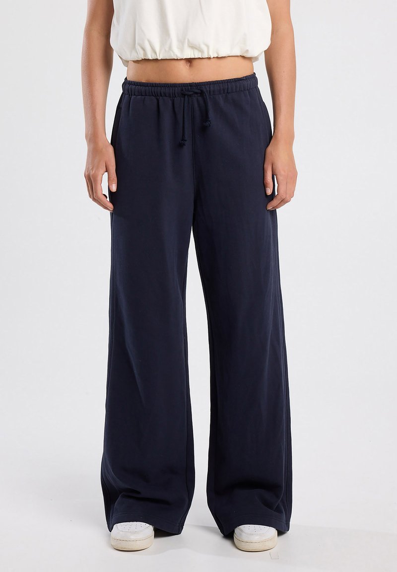 Marineblauwe wijde beenbroek van zachte stof, met een elastische tailleband en een trekkoord. Comfortabele pasvorm tot aan de enkel.