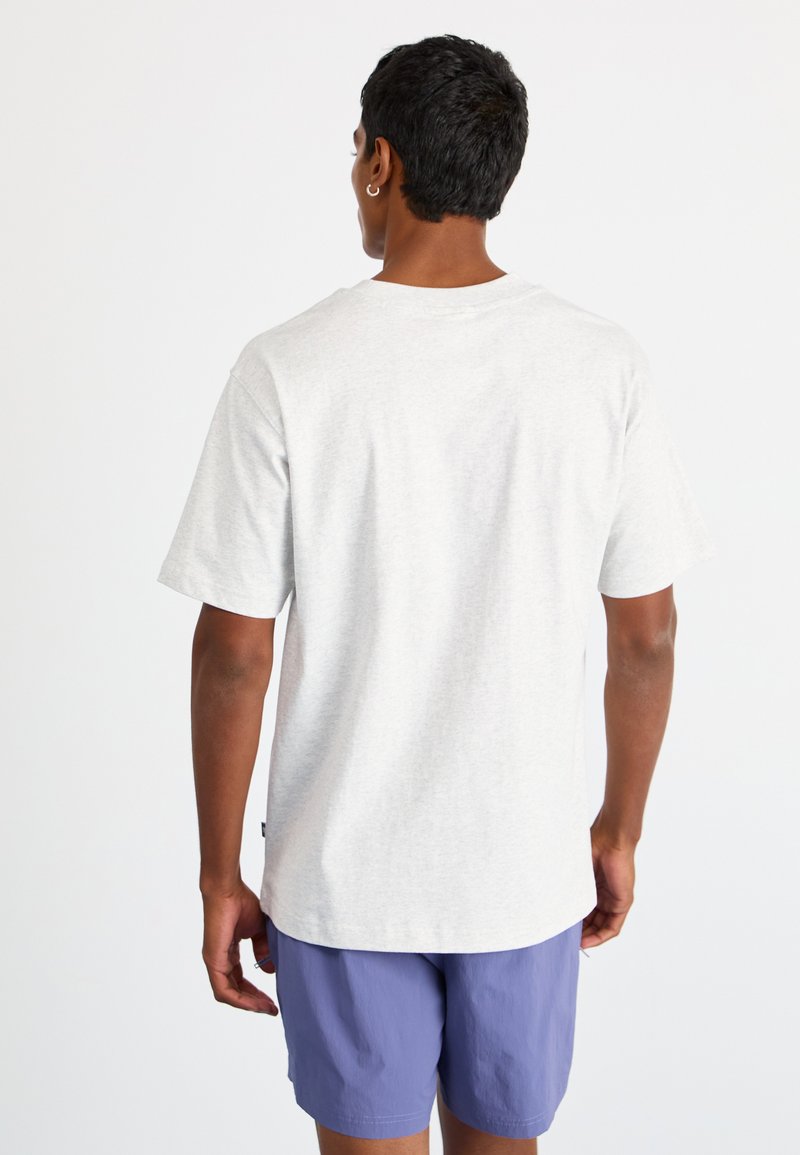 Grijze katoenen T-shirt met korte mouwen en een losse pasvorm, achteraanzicht weergegeven. Draagt een paarse short, met een eenvoudig design en een zachte textuur.