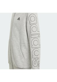 Szary hoodie zapinany na zamek z dużym czarnym napisem "adidas" na rękawie, z kieszenią z przodu i miękkim, teksturowanym materiałem.