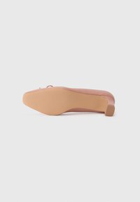 Pink flat shoe with a rounded toe, smooth synthetic upper, beige rubber sole, and textured grip detail on the heel.