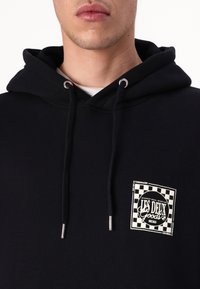 Crna hoodie od mješavine pamuka, sa prednjim džepom, srebrnim grometima i kvadratnom logotip oznakom u bijeloj i crnoj kariranom uzorku.