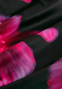 Silkkikangas, jossa on musta tausta ja suuria abstrakteja vaaleanpunaisia ja violetteja kukkakuoseja. Sileä pinta, jossa on hienovarainen kiilto.