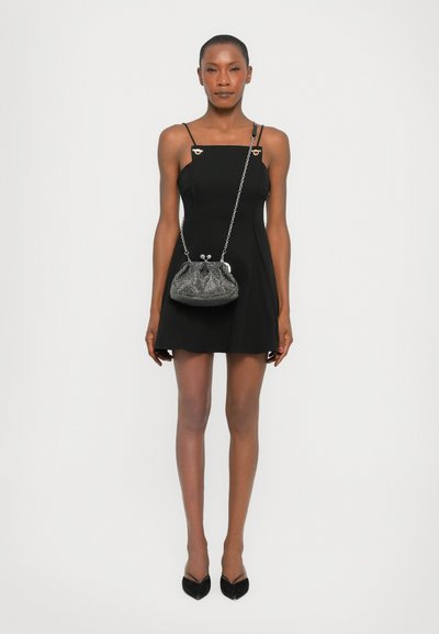 Black dress with thin straps and accent hardware, paired with a metallic silver clutch bag featuring a chain strap and gathered design.
