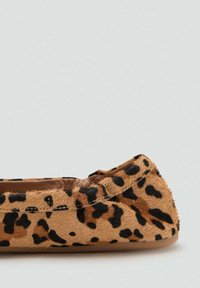 Płaskie buty w panterkę wykonane z teksturowanego materiału przypominającego futro. Charakteryzują się niskim profilem, zaokrąglonym noskiem oraz gładką, wewnętrzną wyściółką.