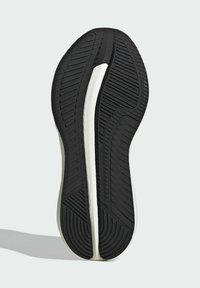 Semelle de chaussure avec une base en caoutchouc noir texturé, une intersemelle blanche et un design courbé présentant des rainures pour l'adhérence.