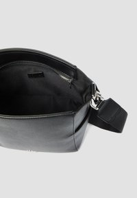 Borsa a spalla in pelle nera con superficie testurizzata, scomparto principale con zip e tracolla regolabile per un trasporto sicuro.