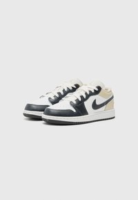 Baskets en cuir blanches et marines avec un profil bas, un bout rond, un laçage à l'avant et une semelle en caoutchouc texturée, présentant un accent beige sur le talon.