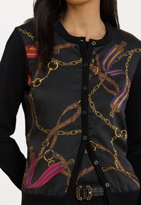 Μαύρο cardigan με πολύχρωμο μοτίβο αλυσίδας και λουριών, με χρυσές λεπτομέρειες, κουμπιά στη μπροστινή πλευρά και λεία υφή υφάσματος.