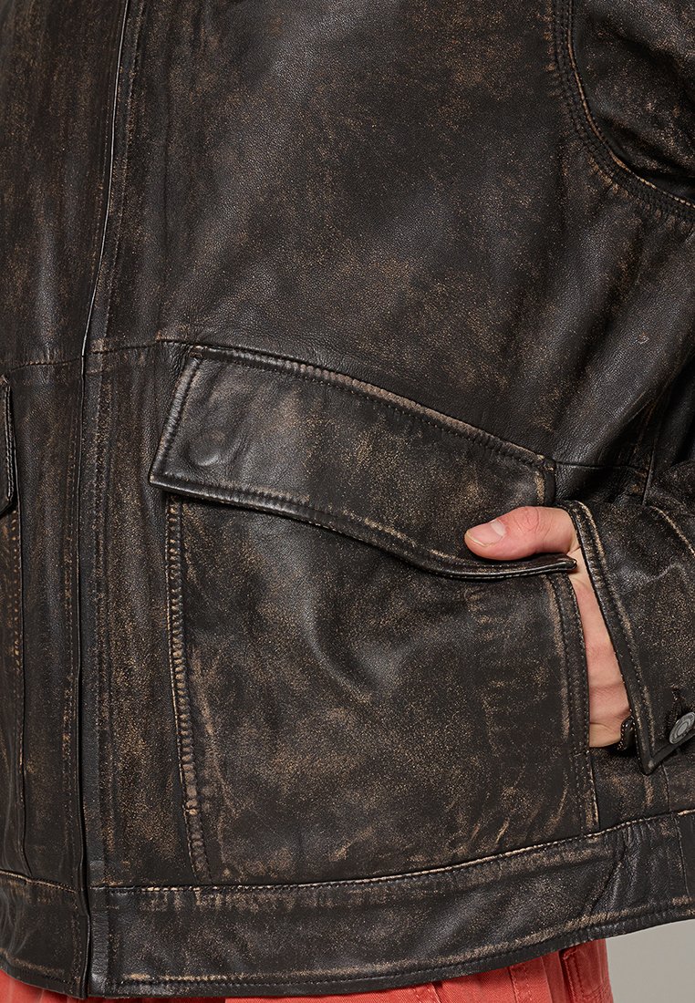 Brązowa skórzana kurtka o postarzanym wykończeniu, z dwoma przednimi kieszeniami, widocznym szyciem i subtelnym połyskiem.