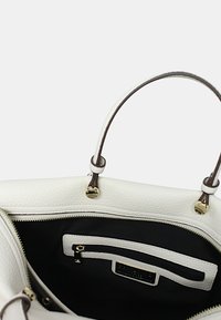 Borsa a mano bianca in pelle con doppi manici marroni, esterno testurizzato, fodera in tessuto nero, tasca interna con zip e dettagli in metallo dorato.