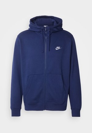 Marineblaue Zip-Hoodie aus weichem Fleece-Stoff, mit einer Fronttasche, gerippten Bündchen und einem weißen Nike-Logo auf der linken Brust.