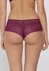 Krajková hipster spodní prádlo v tmavě fialové barvě s vlnkovanými okraji a květinovým vzorem, s nízkým pasem a měkkou, texturovanou tkaninou.
