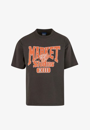 Fekete pamut póló narancsszínű grafikával, amelyen az "MARKET Studios XIII" felirat és egy tigris mintázat látható. Rövid ujjú és kerek nyakú.