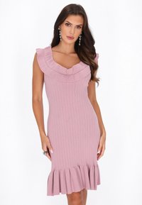 Gebreide jurk in zachtroze met een uitlopende roezelzoom, brede roezel halslijn en een getailleerde silhoutte. Textuurstof met verticale strepen.