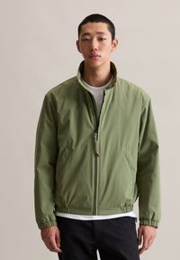 Groene lichtgewicht jas met een hoge kraag, ritssluiting aan de voorkant, zijzakken en elastische manchetten. Gladde textuur en een relaxte pasvorm.