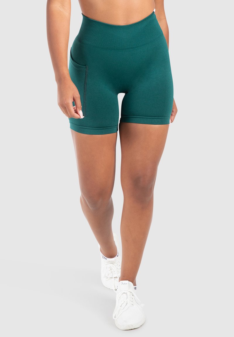 Teal hooggelegen sportshorts met een gladde textuur, voorzien van een zijzak en minimale naaddetailing, gecombineerd met witte sneakers.