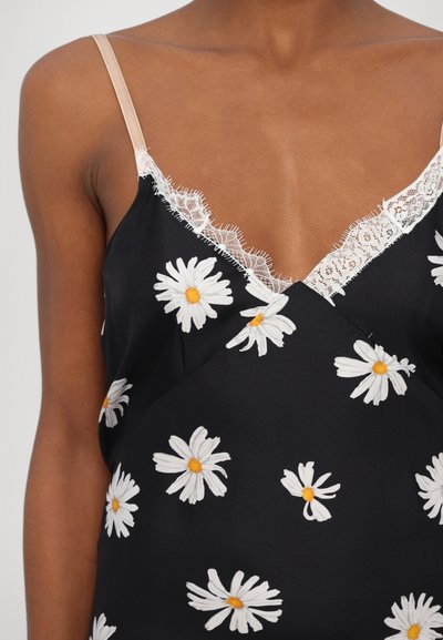 Haut sans manches noir avec broderie de marguerites blanches, featuring un liseré en dentelle au niveau du col, et une texture satinée avec une coupe décontractée.