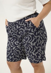 Pantalones cortos azul marino hechos de una tela ligera, con un patrón abstracto en blanco, cinturilla elástica y bolsillos laterales.