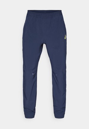 Navy jogger pants made of lightweight fabric, featuring an elastic waistband, side pockets, and a small logo detail in lime green.