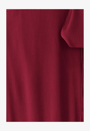 Červená textúrovaná tkanina s vertikálnymi záhybmi, mäkko splývajúca, s hladkým povrchom a jemným leskom. Žiadne viditeľné kovové prvky ani akcenty.