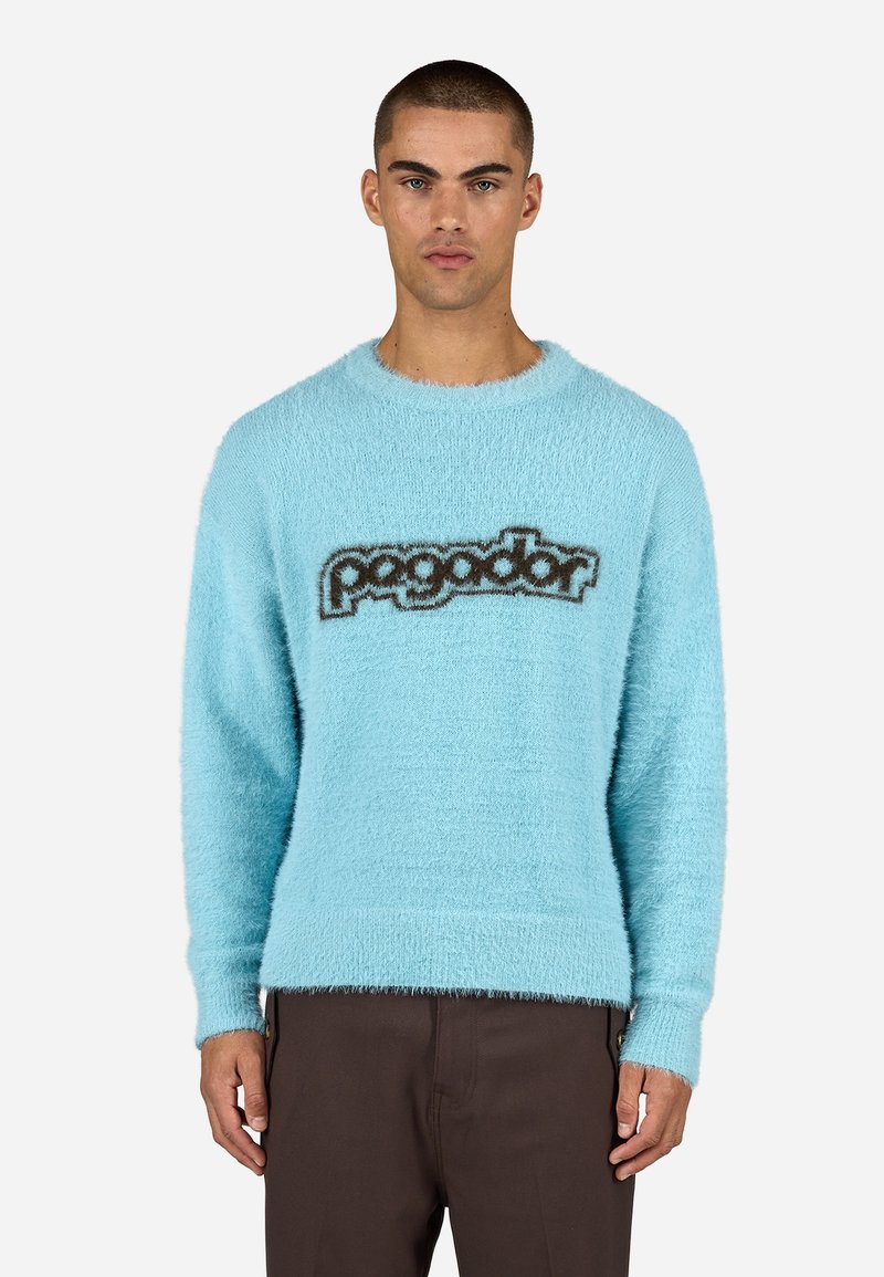Šviesiai mėlynas pūkuotas megztinis su apvalia iškirpte ir ilgomis rankovėmis, su tamsiai ruduo "pagador" logotipu per krūtinę. Tekstūruota medžiaga.