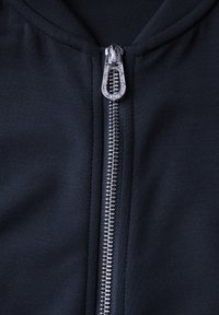 Felpa blu navy con zip in metallo argentato dotata di un tirante a motivo a diamante, tessuto morbido e colletto a costine.