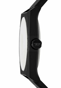 Montre noire au poignet avec un boîtier texturé, un cadran blanc lisse et une couronne ronde noire proéminente sur le côté. Bracelet noir mat attaché.
