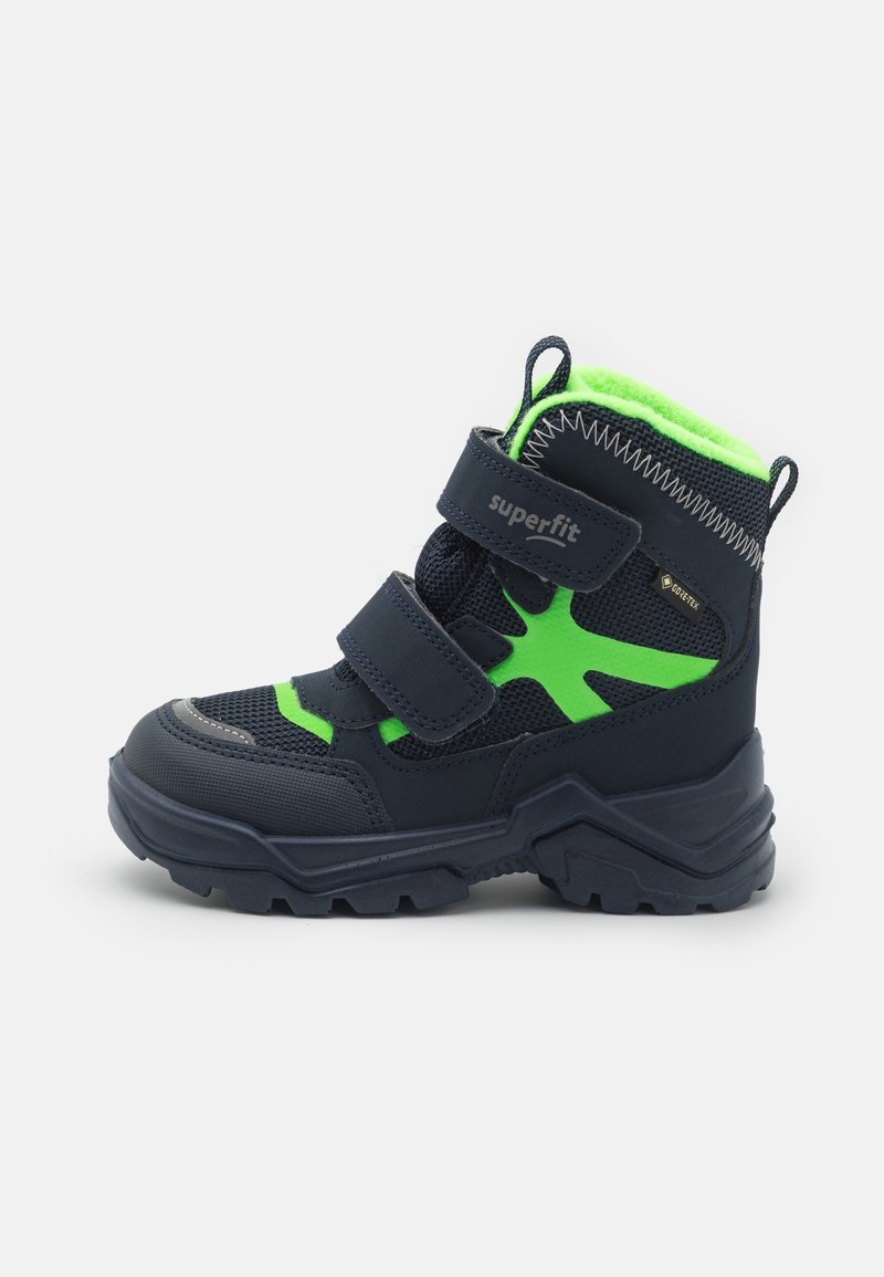 Bottes pour enfants bleu marine avec des accents verts, tige en mesh et semelle en caoutchouc texturée. Equipées de deux bandes Velcro réglables pour un enfilage facile.