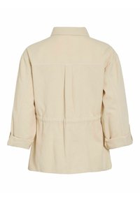 Veste beige à manches longues avec un pli dans le dos, des poignets retroussés et un col, vue de dos sur fond blanc.