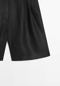 Shorts noirs en tissu léger, dotés d'une coupe décontractée, de poches latérales et d'une texture douce. Design simple sans motifs.
