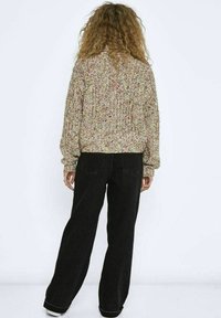 Gehaakte trui met een multicolore patroon, textuurstof en een losse pasvorm, gecombineerd met high-waisted zwarte wijde jeans.