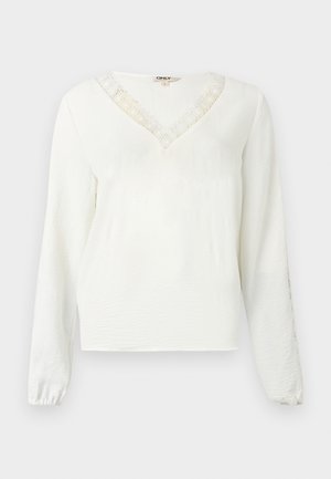 Bílá halenka s dlouhým rukávem a výstřihem do V, zdobená krajkovým lemováním, texturovaným materiálem a elastickými manžetami.